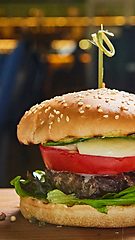 Image showing Beef burger with lettuce and mayonnaise served on a rustic wooden table of counter, with copy space.