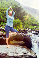 Image showing Woman in yoga asana Vrikshasana tree pose at waterfall outdoors