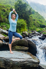Image showing Woman in yoga asana Vrikshasana tree pose at waterfall outdoors