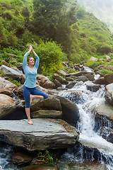 Image showing Woman in yoga asana Vrikshasana tree pose at waterfall outdoors