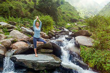 Image showing Woman in yoga asana Vrikshasana tree pose at waterfall outdoors