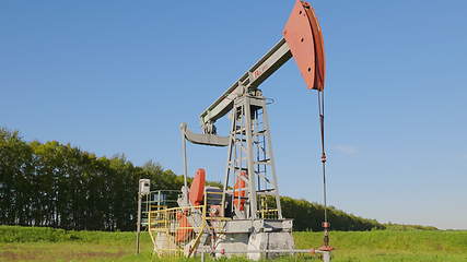 Image showing Operating oil and gas well in oil field, profiled against the blue sky