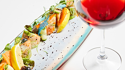 Image showing fried fish rolls with herbs and vegetables on blue plate.