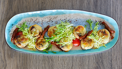 Image showing Fried scallops with butter lemon spicy sauce served with green salad. Top view, copy space.