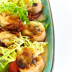 Image showing Fried scallops with butter lemon spicy sauce served with green salad. Top view, copy space.