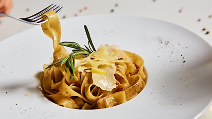 Image showing Close-up italian pasta plate with grated parmesan cheese and basil leaf