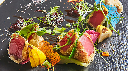Image showing Close up of rare seared Ahi tuna slices with fresh vegetable salad on a plate.