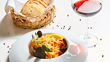 Image showing The cooked mussels and pasta with wine glass.