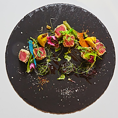 Image showing Close up of rare seared Ahi tuna slices with fresh vegetable salad on a plate.