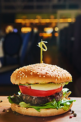 Image showing Beef burger with lettuce and mayonnaise served on a rustic wooden table of counter, with copy space.