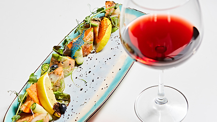 Image showing fried fish rolls with herbs and vegetables on blue plate.