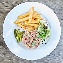 Image showing Meat tartar with french fries and vegetable salad.