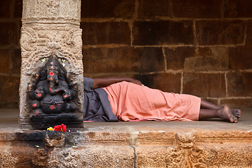 Image showing Man sleeping behing the column with Ganesha images. in Hindu tem