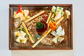 Image showing Cheese selection on wooden rustic board. Cheese platter with different cheeses on wood.