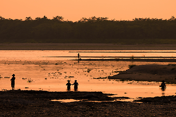 Image showing Asian women fishing in the river, silhouette at sunset