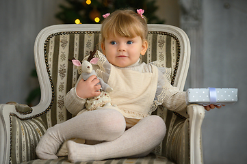 Image showing Little funny girl having fun in a chair in front of Christmas tree