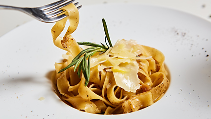 Image showing Close-up italian pasta plate with grated parmesan cheese and basil leaf
