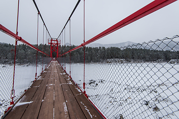 Image showing Suspension hanging bridge above winter frozen river