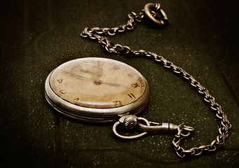 Image showing Old clock with chain lying on rough green surface