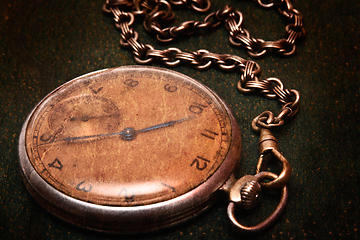 Image showing Old clock with chain lying on rough green surface