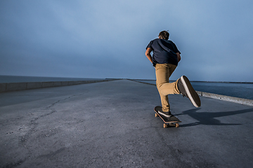 Image showing Skateboarder pushing on a concrete pavement