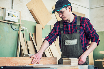 Image showing Construction worker cutting wooden board