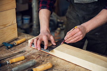 Image showing The worker makes measurements of a wooden board