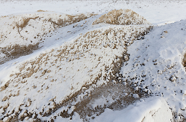 Image showing Sand under the snow - a pile of sand for construction, covered with snow. A close-up photograph in the winter season