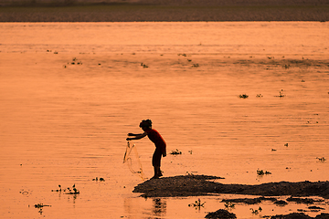 Image showing Asian Woman fishing in the river, silhouette at sunset