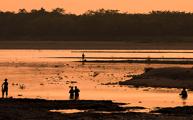 Image showing Asian women fishing in the river, silhouette at sunset