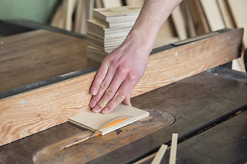 Image showing Construction worker cutting wooden board