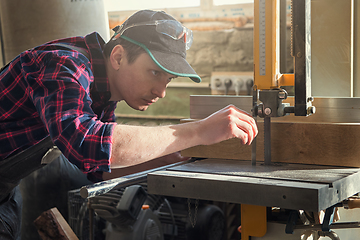 Image showing Construction worker cutting wooden board