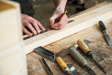 Image showing The worker makes measurements of a wooden board