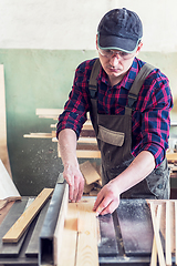 Image showing Construction worker cutting wooden board