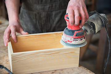 Image showing Worker grinds the wood box