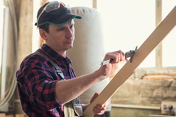 Image showing The worker makes measurements of a wooden board