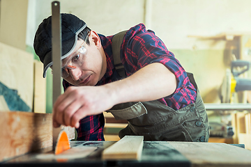 Image showing The worker makes measurements of a wooden board