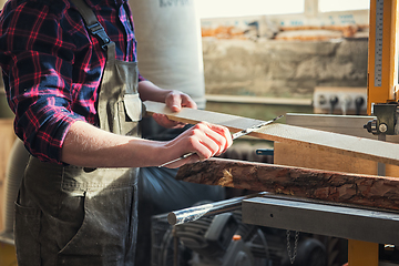 Image showing The worker makes measurements of a wooden board