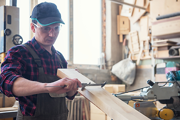 Image showing The worker makes measurements of a wooden board