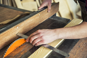 Image showing Construction worker cutting wooden board