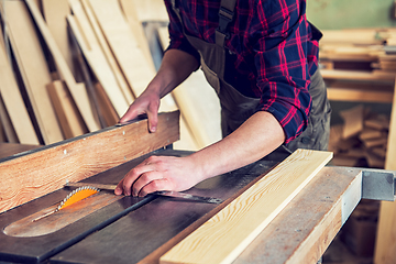 Image showing Construction worker cutting wooden board