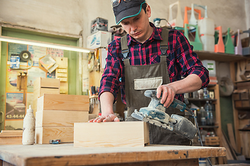 Image showing Worker grinds the wood box