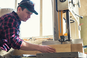 Image showing Construction worker cutting wooden board