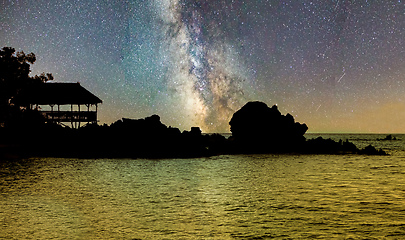 Image showing Silhouette of coast over ocean with starry sky