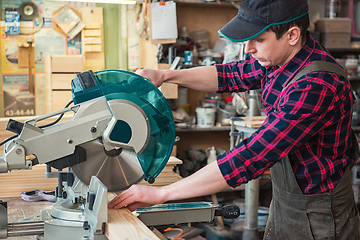 Image showing Construction worker cutting wooden board