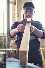 Image showing The worker makes measurements of a wooden board