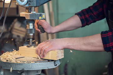 Image showing Carpenters with electric drill machine drilling wooden board