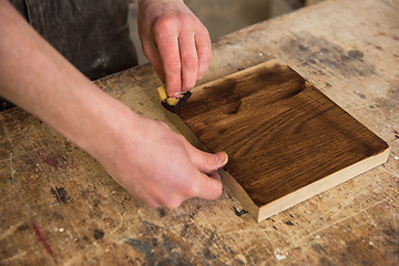 Image showing Carpenter painting wooden