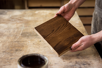 Image showing Carpenter painting wooden