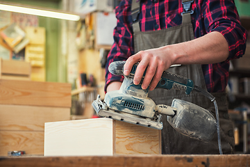 Image showing Worker grinds the wood box